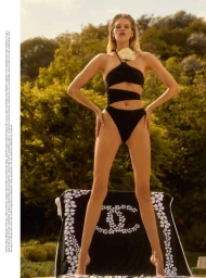 Model Kim Riekenberg in a black cutout swimsuit standing before lush green trees for InStyle Germany.