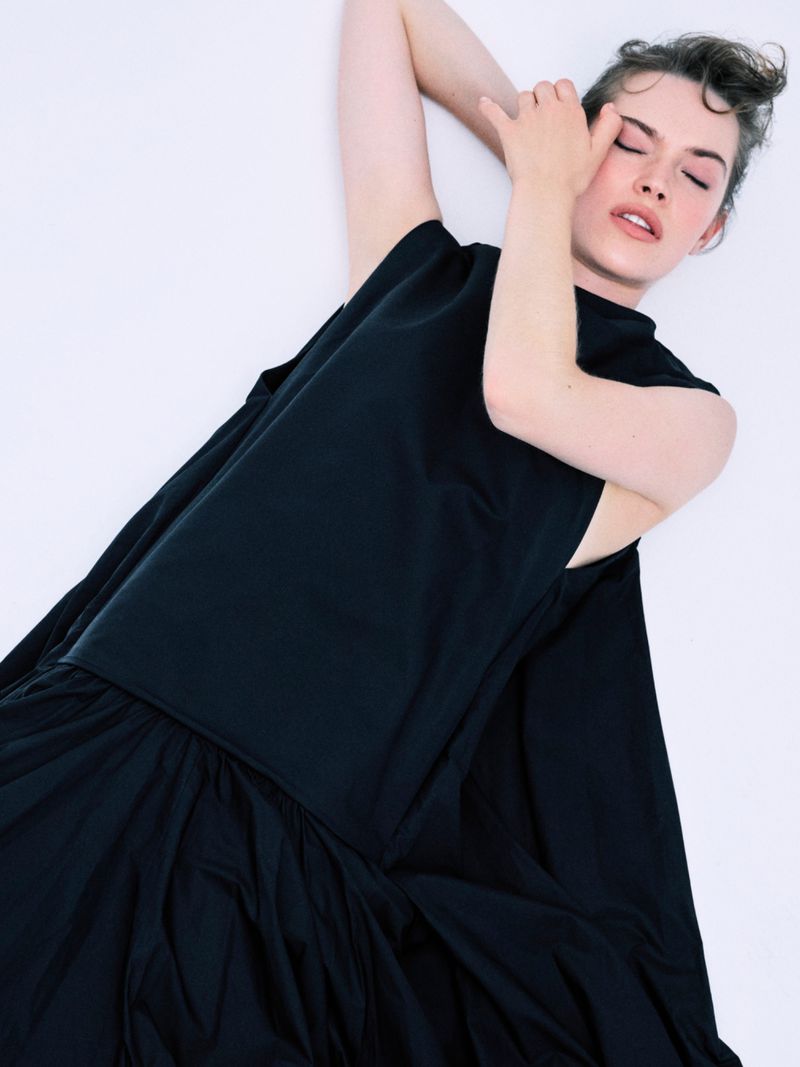 Model Caro Casay in a black sleeveless dress lying against a bright white background for Harper's Bazaar Turkey.