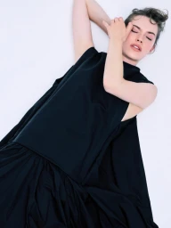 Model Caro Casay in a black sleeveless dress lying against a bright white background for Harper's Bazaar Turkey.