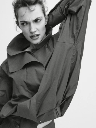 Model Caro Casay in a high-collared dark top with her arm raised against a plain white background for Harper's Bazaar Turkey.