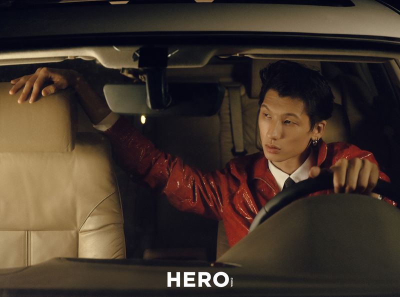 Model in a red jacket sitting inside a car holding the steering wheel for HERO Magazine Summer’s Last Hurrah project
