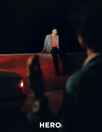 Model seated on a ledge at night with red and dark lighting for HERO Magazine editorial Summer’s Last Hurrah