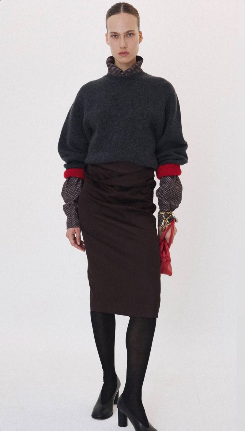Model wearing dark grey sweater, brown skirt, and black tights against white background for Recto fall winter 2026