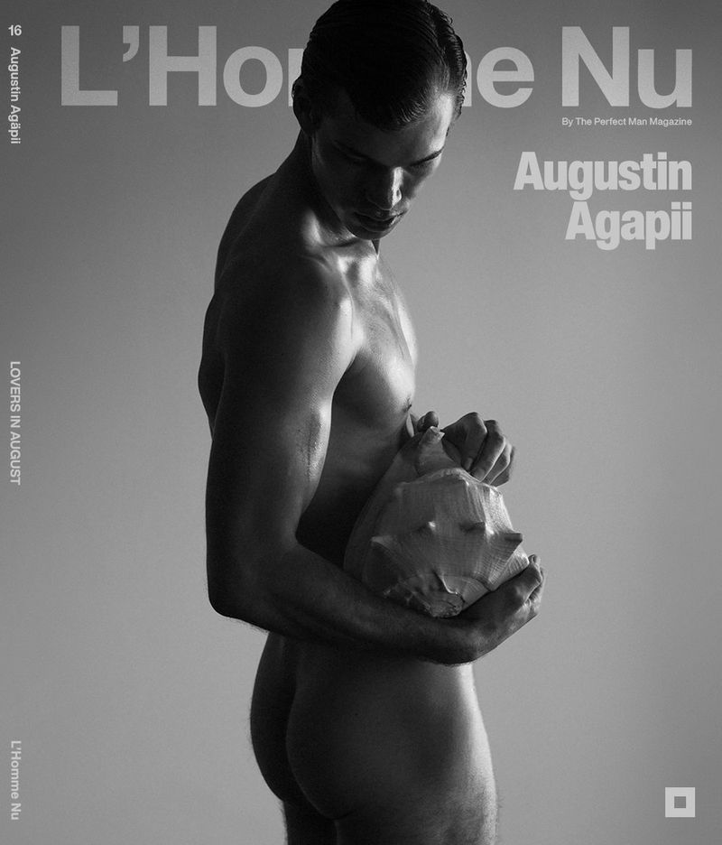 Black and white studio portrait of a nude adult male holding a seashell. The man is partially visible from the side in a studio environment.
