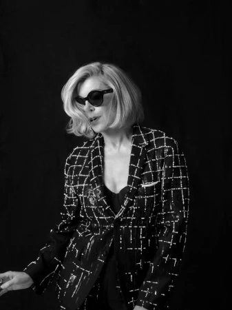 Christine Baranski wearing dark sunglasses and a patterned blazer against a dark background for Telegraph Magazine.