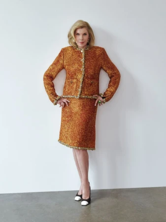 Christine Baranski posing in a textured tweed skirt suit against a plain white studio wall