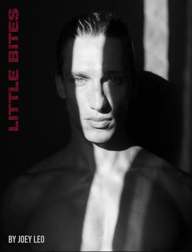 Striking black and white portrait of a handsome adult male with strong lighting and shadows against a dark background.