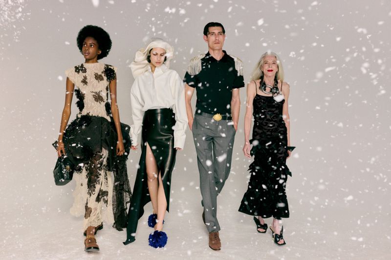 Four diverse models walking together against a white studio background with falling snow effect.