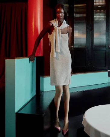 Model Mayor Dutie wearing a silver dress with a sweater tied over shoulders in an interior