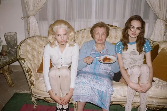 Three women seated on a vintage cream sofa holding a small plate, photographed by Terry Richardson for Enfants Riches Deprimes.