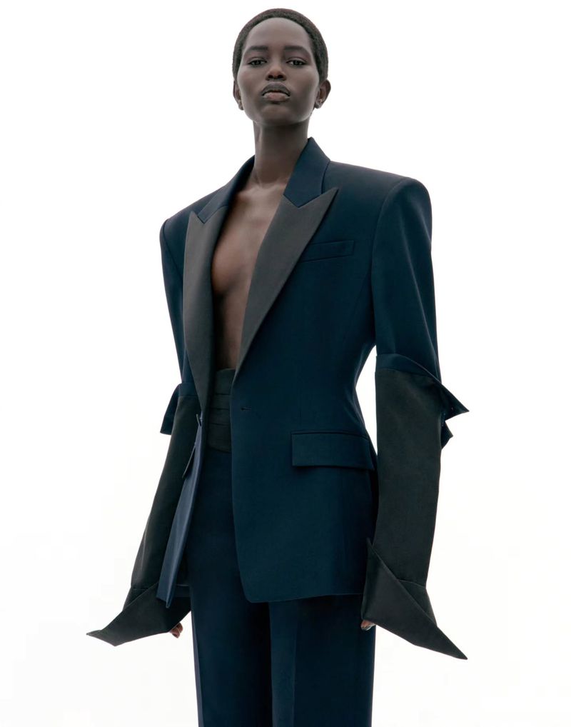 Model wearing a dark tailored blazer with exaggerated lapels against a plain white background.