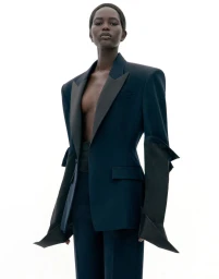 Model wearing a dark tailored blazer with exaggerated lapels against a plain white background.