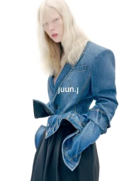 Model with long blonde hair wearing a structured blue denim blazer against a plain white background for Juun.J