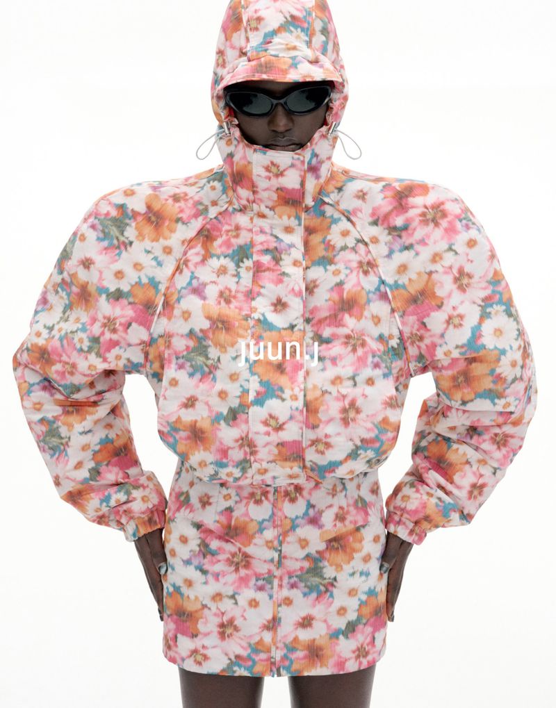 Model wearing floral print hooded jacket with padded shoulders and sunglasses against a plain white background for Juun.J S/S27