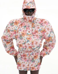 Model wearing floral print hooded jacket with padded shoulders and sunglasses against a plain white background for Juun.J S/S27