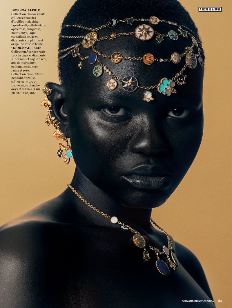 Portrait of a dark-skinned woman with gold head jewelry, a necklace, and earrings against a golden background in a fashion style.