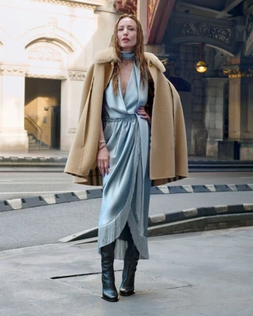 Woman in pale blue dress and camel coat standing on a city street for Burberry campaign shot by Jack Day