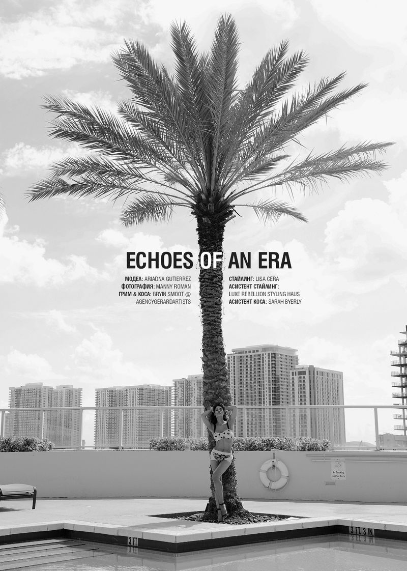 Monochrome fashion shot of a woman in swimwear leaning against a palm tree near a pool with city buildings in the background.