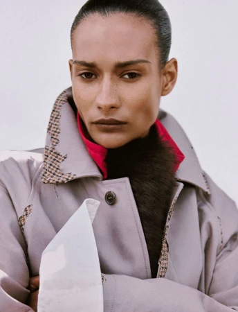 Model with slicked-back hair wearing a grey coat with houndstooth lapels and a pink collar for Numéro France