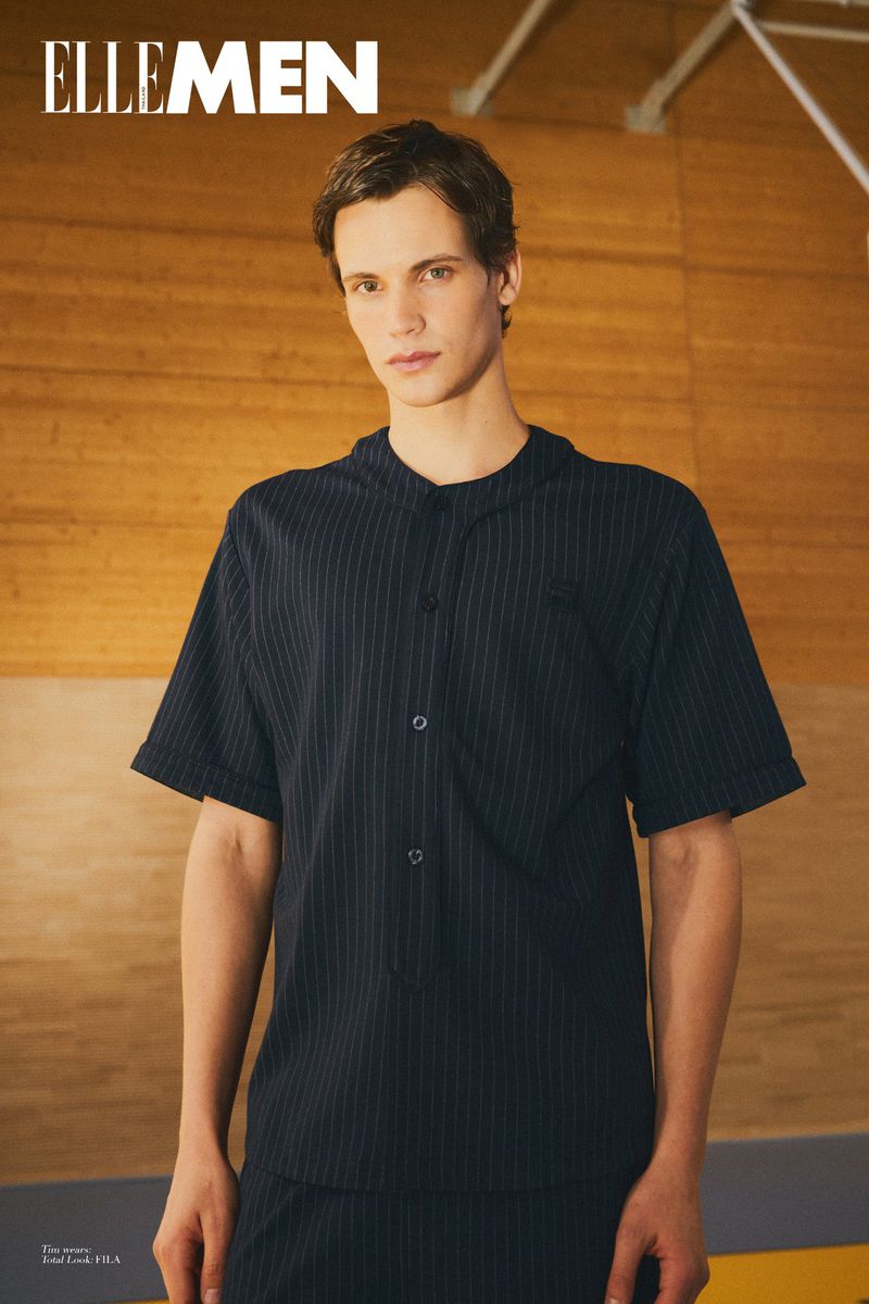 Model wearing dark pinstriped short sleeve button shirt against wooden wall background