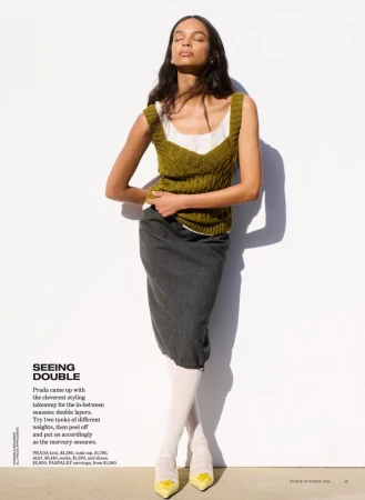 Model wearing an olive green knit tank top and grey skirt against a bright white background for Vogue Australia