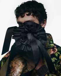 Model Saul Symon with face obscured by a black satin flower ornament for Fantastic Man, photographed by Janneke Van der Hagen.