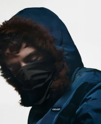 Model wearing a blue hooded jacket and black face mask against a white background for Fantastic Man