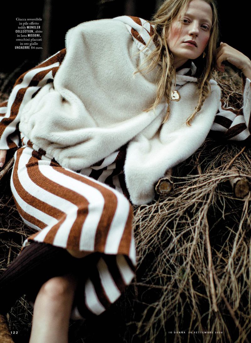 Model in brown and white striped patterned knitwear resting on branches for iO Donna magazine editorial project Alta quota
