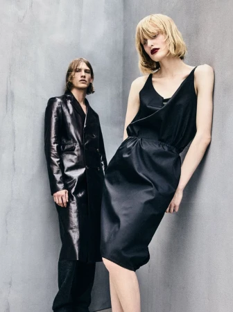 Two models posing against a grey textured concrete wall wearing black apparel for Mixte
