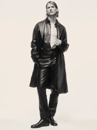 Model in black leather coat and trousers against a pale background for the Mixte Perfect Strangers project
