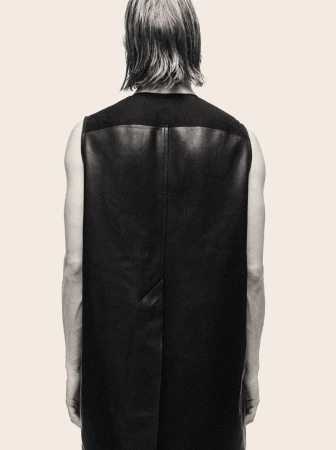 Model seen from behind wearing a black leather sleeveless top against a pale cream background