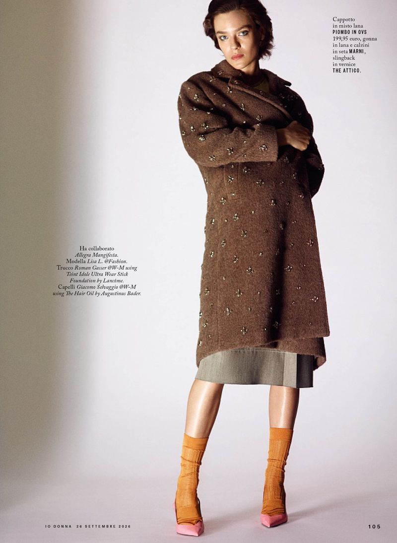Model wearing a brown wool coat and orange socks against a white studio background for iO Donna editorial