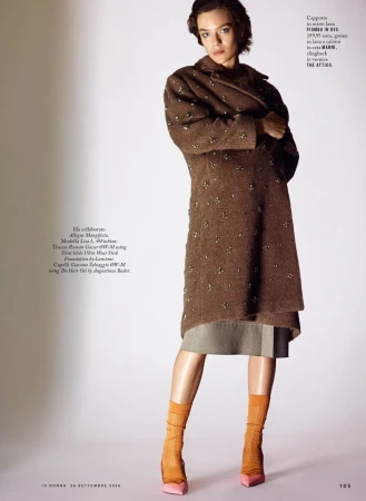 Model wearing a brown wool coat and orange socks against a white studio background for iO Donna editorial