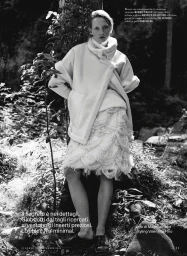Model Marie Louwes in a white fluffy coat and fringe skirt leaning against a tree in a forest for iO Donna