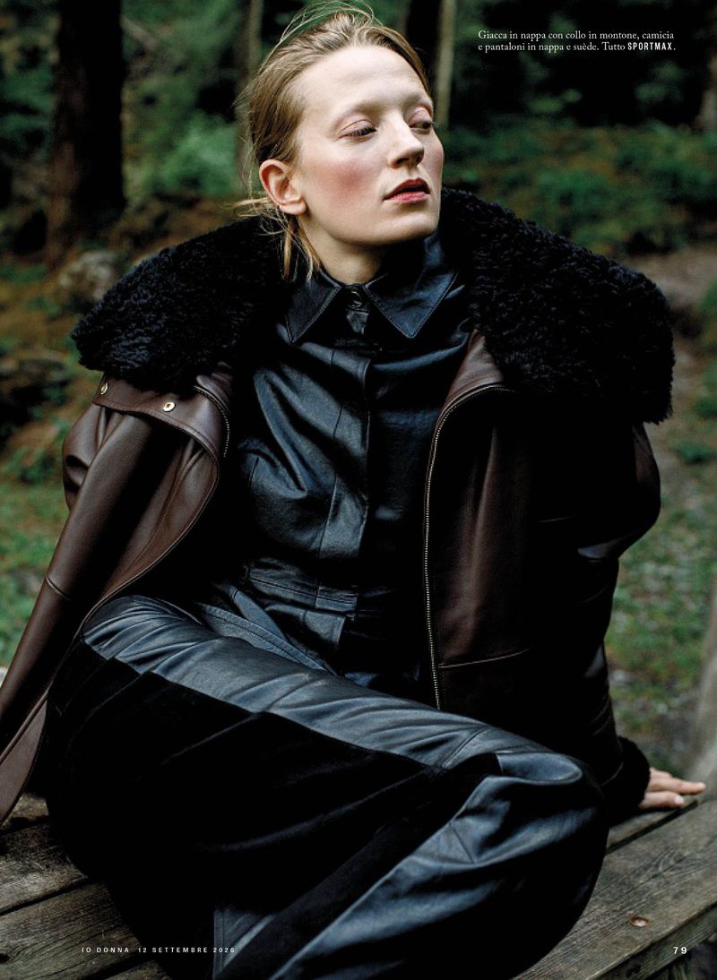 Model wearing a dark leather jacket with a fur collar and leather trousers in a forest setting for iO Donna project Wild