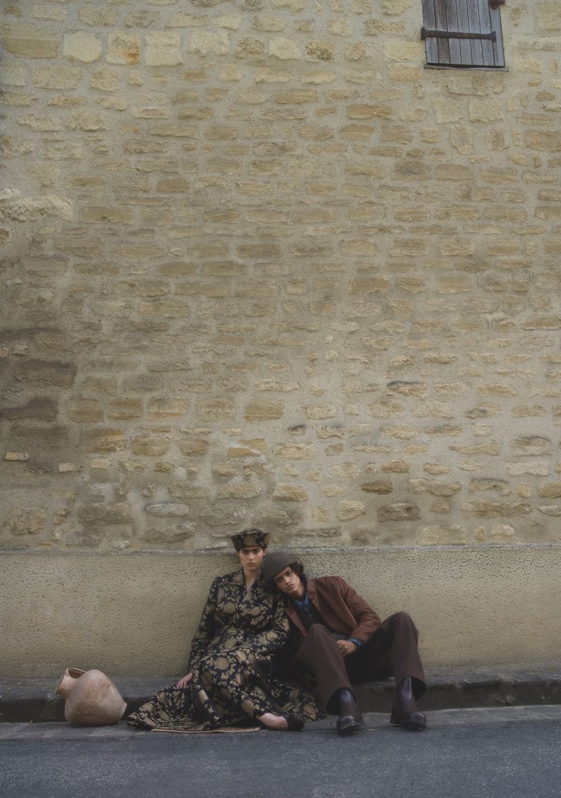 Two models seated against a rustic stone wall for Crash Magazine editorial photographed by Michal Chelbin