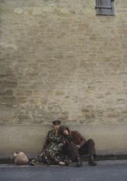 Two models seated against a rustic stone wall for Crash Magazine editorial photographed by Michal Chelbin