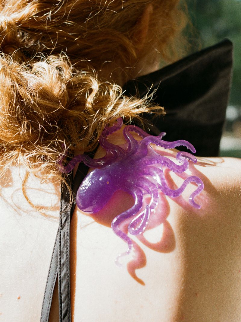 Close-up of a person's shoulder with a translucent purple octopus accessory resting on skin.