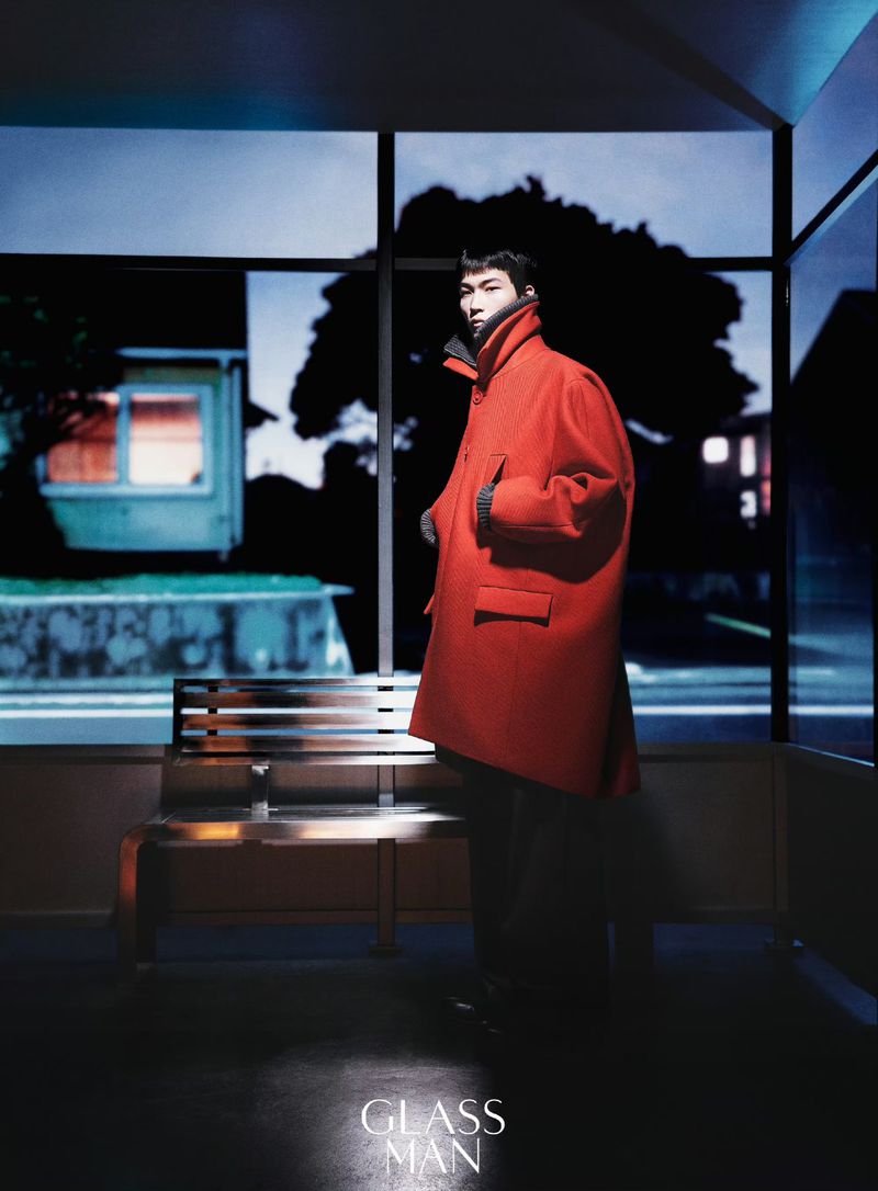 Model wearing a bright red winter coat standing inside a bus shelter at night for Glass Man China