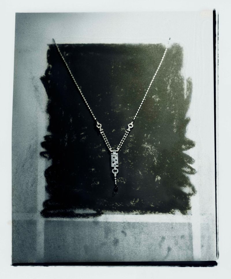 Silver pendant necklace displayed against a dark charcoal textured block background captured by photographer Bex Day.