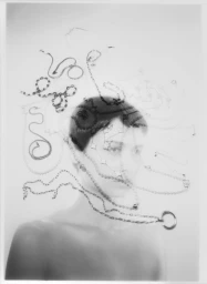 Monochrome multiple exposure portrait of a person layered with delicate chains and jewellery against a light background.
