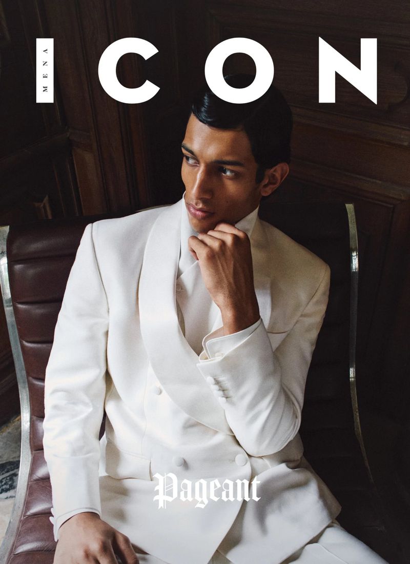 A man in a white suit jacket sitting on a brown leather armchair for ICON Magazine Mena.
