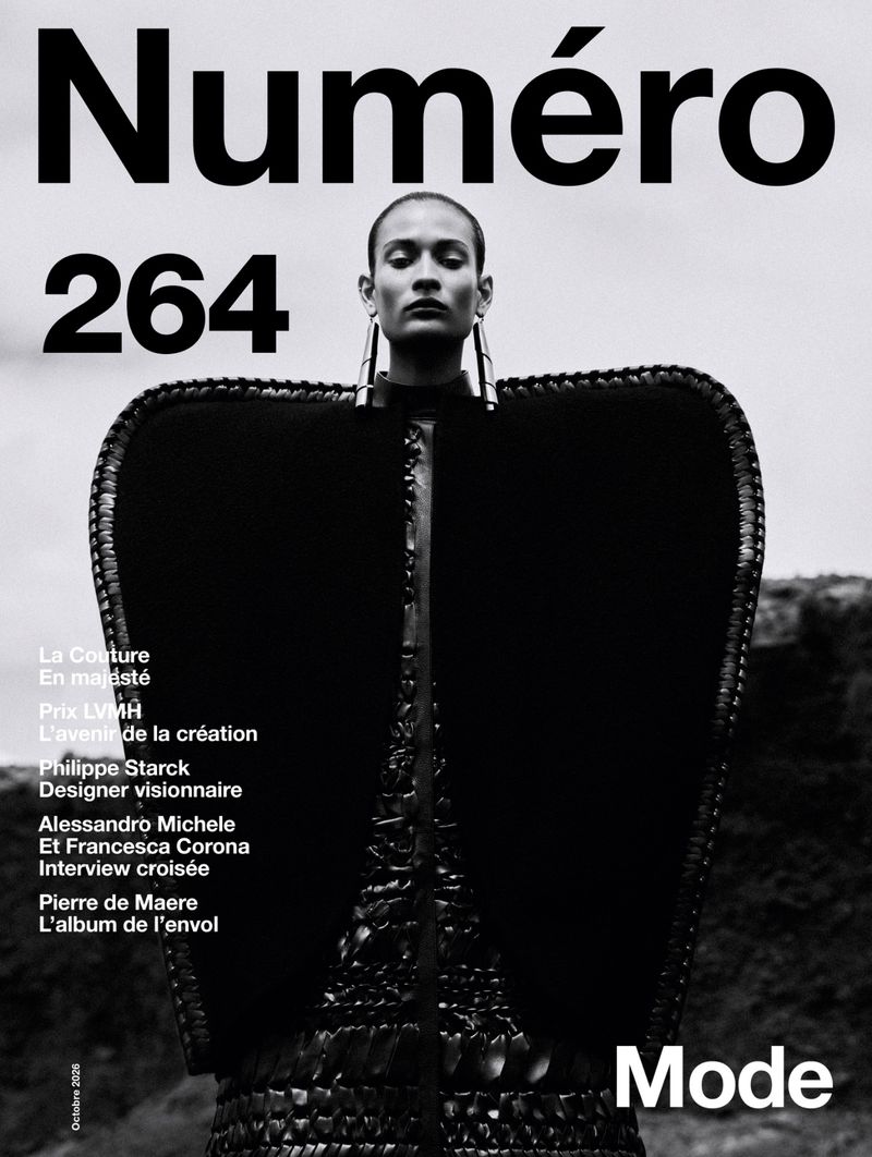 Monochrome magazine cover featuring a model in architectural black outerwear against an overcast sky