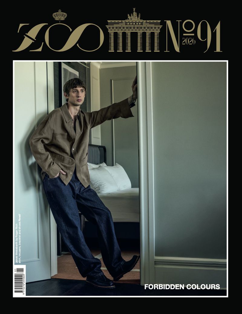 Model leaning against a doorway in a brown shirt and dark trousers for Zoo Magazine Issue 91 cover.
