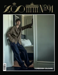 Model leaning against a doorway in a brown shirt and dark trousers for Zoo Magazine Issue 91 cover.