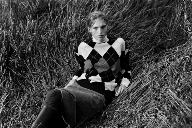 Model in argyle sweater seated in tall grass for Massimo Dutti campaign