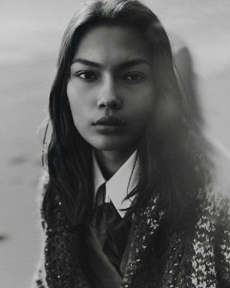 Portrait of a model wearing a white shirt and textured patterned coat