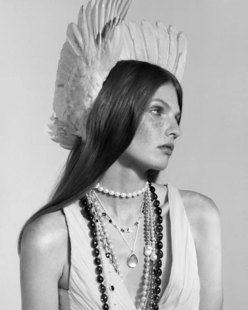 Model wearing feathered headpiece and layered pearl and gemstone necklaces for Ippolita Campaign