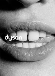 Close-up black and white image of a person smiling showing white teeth and lips with the Dyson logo overlaid.