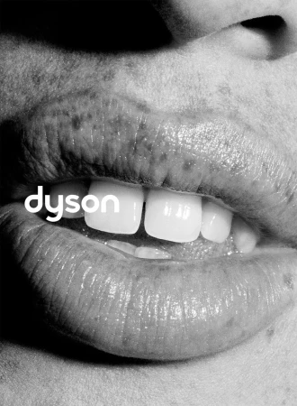 Close-up monochrome macro photograph of lips and teeth featuring white Dyson branding overlaid on the left.